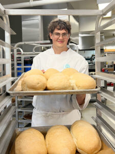 Food Services Intern at RockRidge Canyon racks fresh bread in the bakery